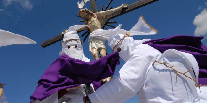 Easter traditions in Italy during a Holy Week procession with hooded brotherhood members carrying a crucifix